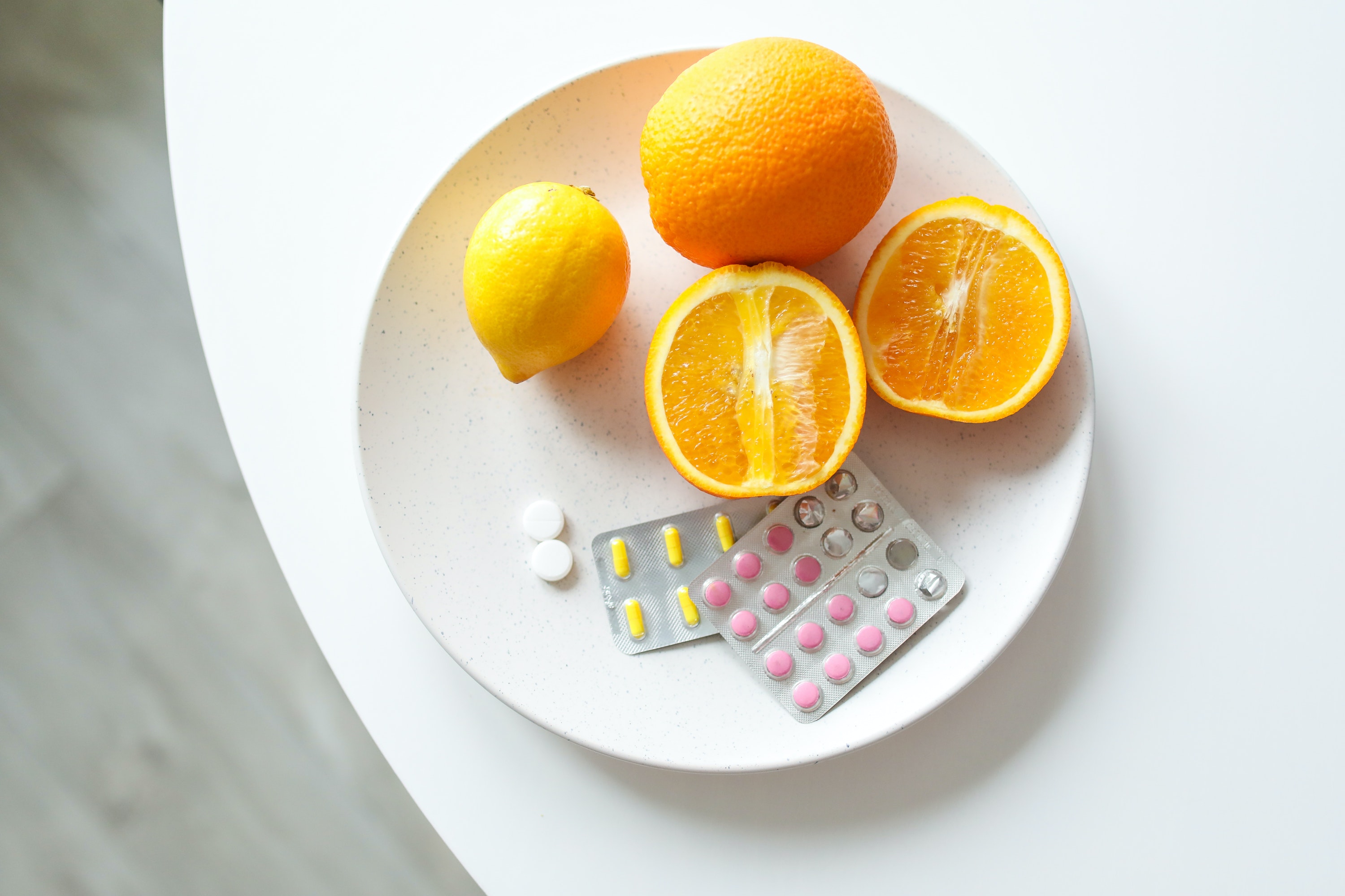 Um prato com remédios em pílulas e laranjas cortadas